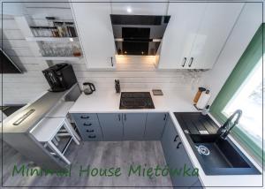 a tiny house kitchen with white cabinets and a sink at Miętówka in Godziszka