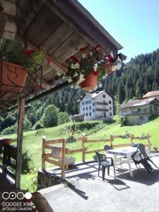 une terrasse avec une table et des chaises ainsi qu'une maison dans l'établissement B&B SòT AL PIZ, à Sagron Mis