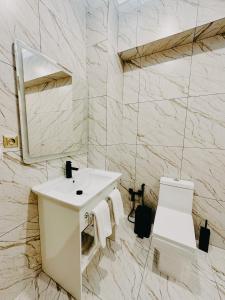 a white bathroom with a sink and a mirror at DAMIR HOTEL in Nukus