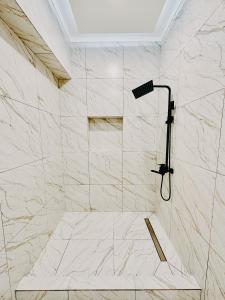 y baño con ducha y paredes de mármol blanco. en DAMIR HOTEL, en Nukus