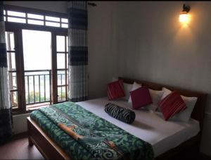 un letto con cuscini sopra in una stanza con finestra di King's Lodge a Nuwara Eliya