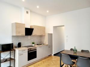 - une cuisine avec des placards blancs, une table et des chaises dans l'établissement Kienmayer Apartment Vienna, à Vienne