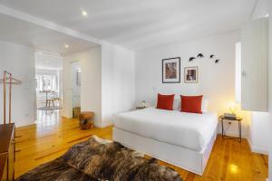 ein weißes Schlafzimmer mit einem großen weißen Bett und orangefarbenen Kissen in der Unterkunft Lisbon's Horizon Retreat: A View to Remember in Lissabon