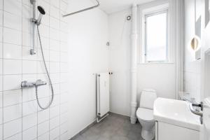 a white bathroom with a shower and a toilet at Come Stay - With Family or Friends in the heart of Aarhus in Aarhus +13 photos