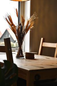 een houten tafel met een vaas met bloemen erop bij De Viool Appartementen in Buren