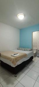 a bed in a room with a blue wall at Pousada Praia Avenida in Maceió