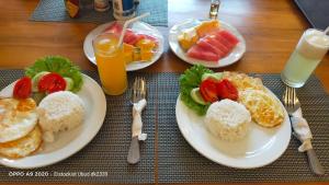 a table with two plates of breakfast foods and fruit at DANU HOUSE UBUD in Ubud