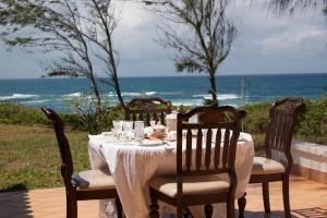 a table with a white tablecloth and chairs and the ocean at Kilulu Luxury Island, Watamu in Watamu