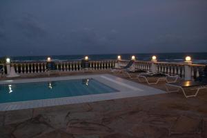 a swimming pool with chairs and the ocean at night at Kilulu Luxury Island, Watamu in Watamu