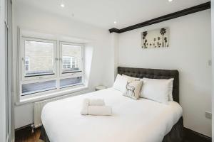 a bedroom with a large white bed with a window at Stylish & Peaceful Covent Garden Apartment in London