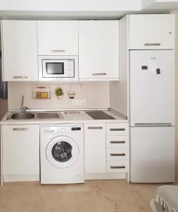 a white kitchen with a washing machine and a microwave at Sol y Arte Suites Málaga Centro in Málaga