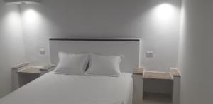 1 cama blanca con 2 almohadas en una habitación en Beach Houses, en Sfax