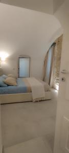 Habitación blanca con cama y espejo en Itinerario Barocco en Ragusa