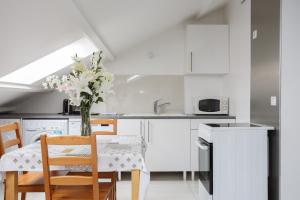 a kitchen with white cabinets and a table with a vase of flowers at Le blanc gauche BAT A 3ème étage in Le Blanc-Mesnil