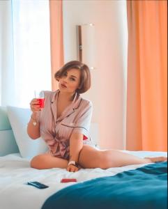 a woman sitting on a bed holding a cup of coffee at PANORAMA ORBI City Center Suite Sea View in Batumi