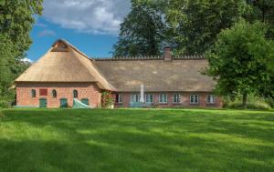 a brick house with a thatched roof on a lawn at Reetdach-Oase in Brarupholz