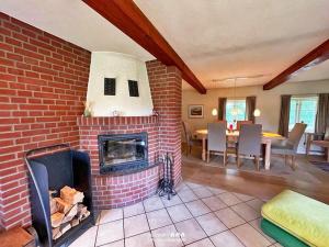 a living room with a brick fireplace and a dining room at Reetdach-Oase in Brarupholz +17 photos