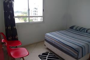 1 dormitorio con cama, silla roja y ventana en Hermoso Departamento Con Vista al Río y Parrilla en Posadas
