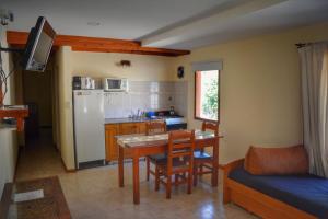 cocina con mesa, sillas y nevera en Complejo Moquehue en Villa Pehuenia