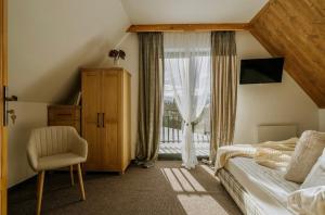 um quarto com uma cama, uma janela e uma cadeira em Cichy Brzyzek em Biały Dunajec