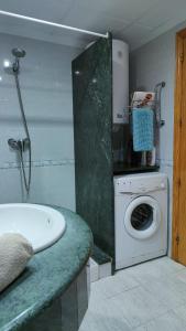y baño con bañera y lavadora. en Apartamentos Montsià Mar, en Sant Carles de la Ràpita