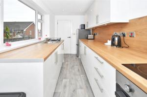 a kitchen with white cabinets and a wooden counter top at Townhouse @ 20 Penkhull New Road Stoke in Stoke on Trent