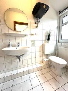 ein Badezimmer mit einem Waschbecken, einem WC und einem Spiegel in der Unterkunft Monteur-Zimmervermietung Visselhövede in Visselhövede
