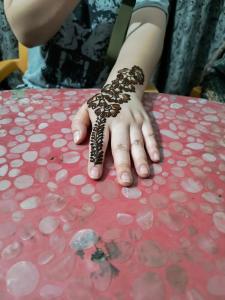 a person with henna on their hand sitting at a table at Holiday Home Stay in Khajurāho