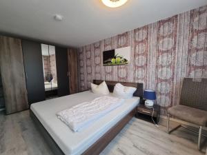 a bedroom with a white bed and a chair at Ferienwohnung Villa Totti Lucas Stube in Neßmersiel