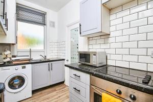 a white kitchen with a microwave and a sink at 5 minutes from Leeds City Centre - Parking in Leeds