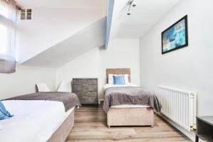 2 Betten in einem Schlafzimmer mit weißen Wänden und Holzböden in der Unterkunft 5 minutes from Leeds City Centre - Parking in Leeds
