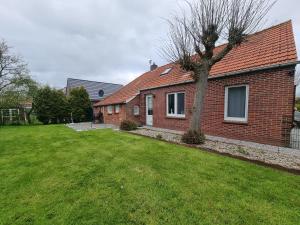 a red brick house with a tree in the yard at Ferienwohnung Villa Totti Lucas Stube in Neßmersiel