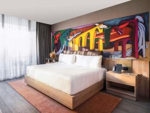 Mondrian Mexico City Condesa في مدينة ميكسيكو: غرفة نوم بسرير كبير عليها لوحة على الحائط