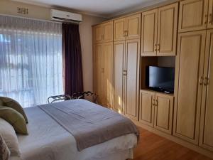 1 dormitorio con 1 cama y TV de pantalla plana en Ringwood Villa, en Ciudad del Cabo