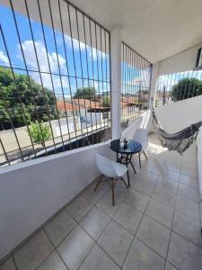 d'un balcon avec une table, des chaises et des fenêtres. dans l'établissement Sua casa em Maceió, à Maceió