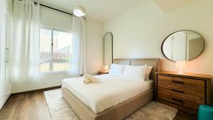 a bedroom with a bed and a mirror and a window at Tranquil 1BR Garden Retreat Dubai Greens in Dubai