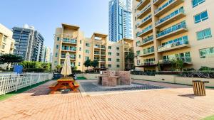 un patio con mesa y sombrilla frente a un edificio en Tranquil 1BR Garden Retreat Dubai Greens, en Dubái