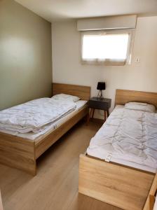 two twin beds in a room with a window at Le Bas Champ in Favières