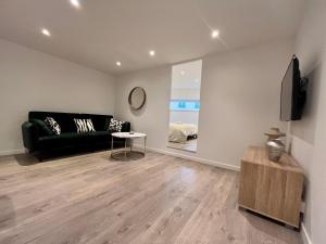 Una sala de estar con un sofá negro y un televisor. en Suite Maël - Check in h24 - Wifi, en Lyon