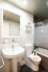 a bathroom with a sink and a toilet and a mirror at SeaHomes Vacations - ACACIAS Beach&Chic in Lloret de Mar