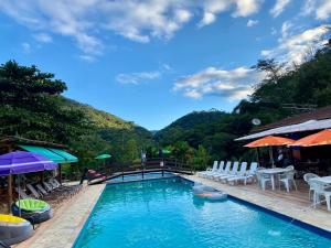 a swimming pool with chairs and umbrellas on a resort at Estação Serramar in Lumiar