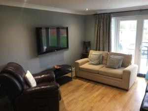 uma sala de estar com um sofá e uma televisão em Still Waters em Hill Head