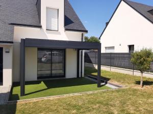 a house with a black roof and a green lawn at Maison TY PRAD bord de mer in Sarzeau