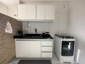 a kitchen with white cabinets and a sink and a stove at Mirante Cidade in Vitória da Conquista