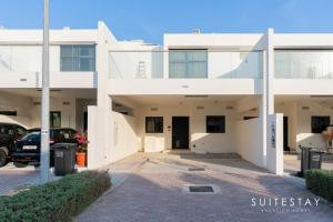 a white building with a car parked in the driveway at Experience Comfort in Our Charming 3-Bedroom Villa in Dubai