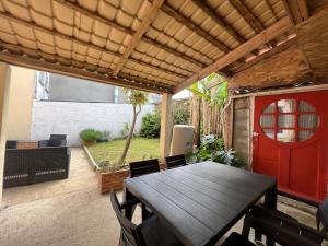 d'une terrasse avec une table en bois et une porte rouge. dans l'établissement RÉF 398 - HENNEBONT maison de ville de caractère avec jardinet et patio, à Hennebont