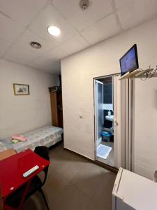 Hostal Milan في أليكانتي: غرفة بها سرير وتلفزيون على الحائط