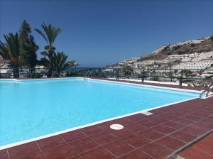 a large swimming pool with a mountain in the background at La casita de Ángela in Puerto Rico de Gran Canaria