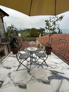 un patio con mesa, 2 sillas y sombrilla en HEATHER'S HOME 108 - Appartamento vista mozzafiato en Bassano del Grappa