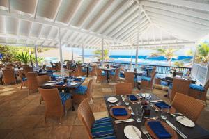 um restaurante com mesas e cadeiras e o oceano em The Atlantis Historic Inn em Saint Joseph